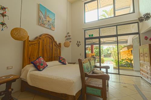 um quarto com uma cama, uma cadeira e uma janela em Hotel Boutique Casa Copal em Ajijic