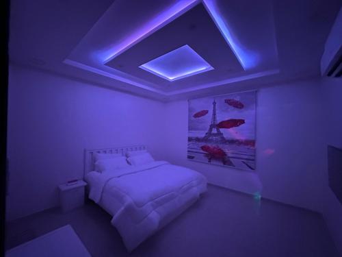 a bedroom with a bed with a purple lighting at شاليه استكنان in Ash Shiqqah
