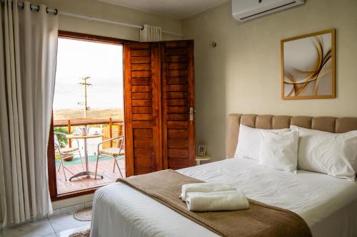 a bedroom with a bed with a view of a balcony at Pousada Loft vista da serra in Serra de São Bento