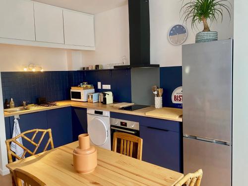 une cuisine avec des placards bleus et une table en bois dans l'établissement Le Central - Coeur historique - Netflix/Disney+, à Soissons