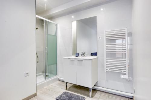 ein weißes Bad mit einem Waschbecken und einer Dusche in der Unterkunft Le refuge familial • Proche Disneyland in Villiers-sur-Marne
