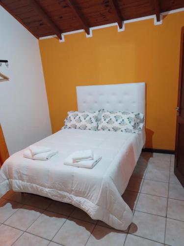 a bed with white sheets and pillows in a room at Cabañas Monik in El Calafate