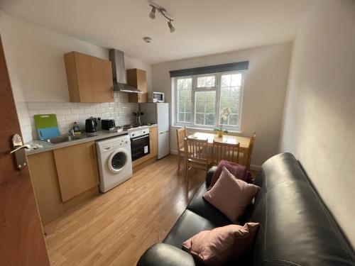 a living room with a couch and a kitchen at Pinner apartments in Pinner