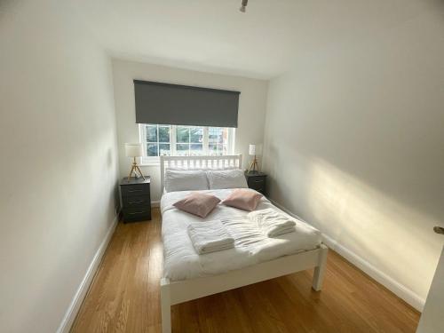 a bedroom with a bed with white sheets and a window at Pinner apartments in Pinner