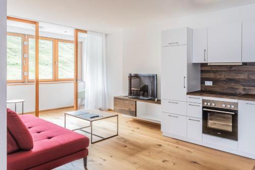 een woonkamer met een rode bank en een keuken bij Berg Aparts Faschina - 05 - b42791 in Fontanella