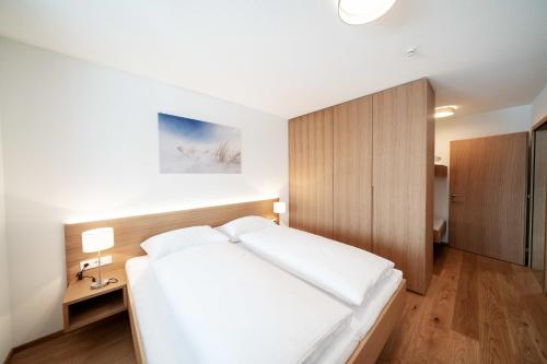 Schlafzimmer mit einem weißen Bett und einem Holzschrank in der Unterkunft Berg Aparts Faschina - 08 - b42792 in Fontanella