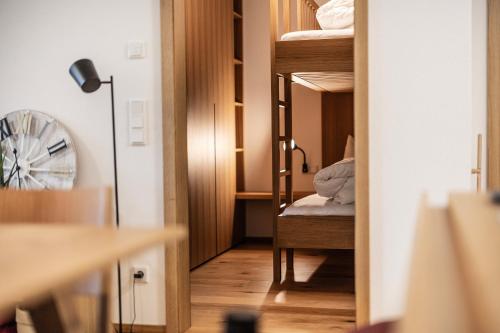 Zimmer mit Etagenbetten und einem Zimmer mit einem Ventilator. in der Unterkunft Berg Aparts Faschina - 09 - in Fontanella