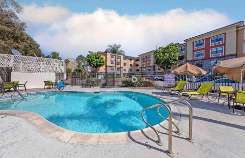 a swimming pool with chairs and tables and buildings at Extended Stay America Suites - Orange County - Anaheim Convention Center in Anaheim