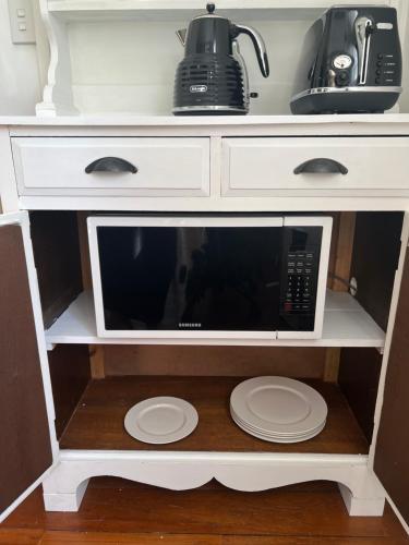 a microwave oven on a shelf with plates on it at The Wash-House historic Cottage Close to Hobbiton in Matamata