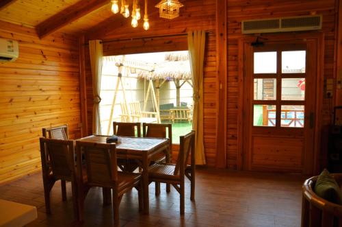 a dining room with a wooden table and chairs at شاليهات الأكواخ الثلاثة in Khalij Salman