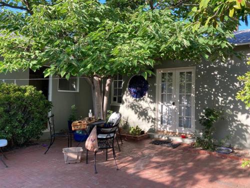 a patio with chairs and a tree in front of a house at Gorgeous boho bungalow in the heart of Pasadena in Pasadena