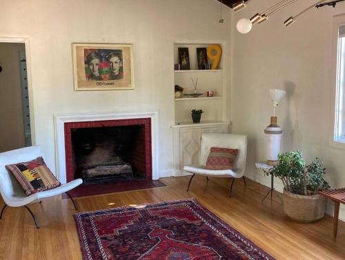 a living room with two chairs and a fireplace at Gorgeous boho bungalow in the heart of Pasadena in Pasadena
