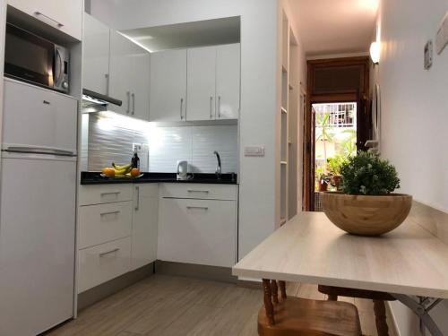 una cucina con mobili bianchi e un tavolo di legno di Green Beach Las Canteras a Las Palmas de Gran Canaria