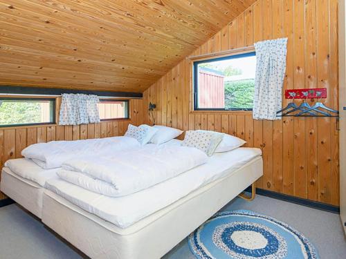 a bedroom with a large bed in a wooden cabin at Holiday home Sydals LXXXIX in Neder Lysabild