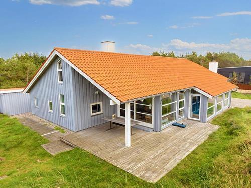 an orange roofed shed with a wooden deck at 12 person holiday home in Thisted in Klitmøller