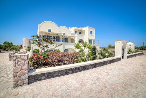 a large white house with flowers in front of it at Monolithia in Kamari