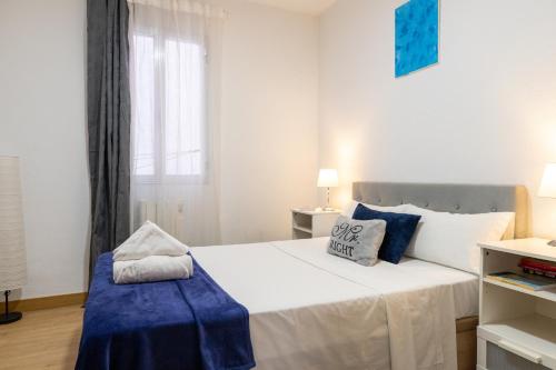 una camera da letto con un grande letto bianco con accenti blu di Pacífico Retiro a Madrid