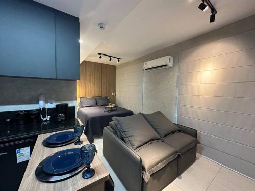 ein kleines Wohnzimmer mit einem Sofa und einem Bett in der Unterkunft Studio Aconchegante e Completo in Ribeirão Preto