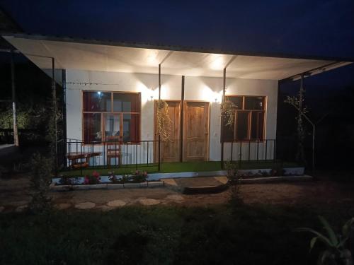 a small house with a porch at night at CABAÑAS GOLDEN TANAGER in Mindo