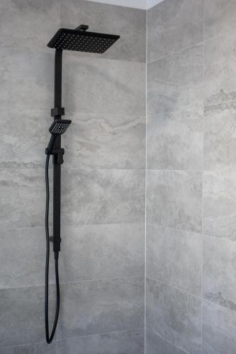 a shower with a black shower head on a wall at Barrington Riverside Cottages in Barrington