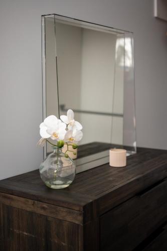 a vase of flowers on a wooden table with a mirror at Barrington Riverside Cottages in Barrington