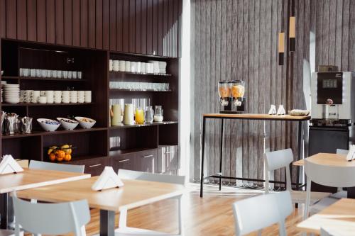 un restaurante con mesas y sillas blancas y una barra en Hotel Barda Sur en General Roca