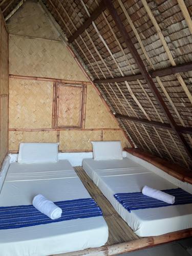 two beds in a straw roofed room with blue mats at Borac Bay View in Borac