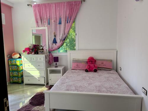 a bedroom with a white bed with a pink teddy bear on it at Villa Begdour à 30Mints de Tanger in Tangier