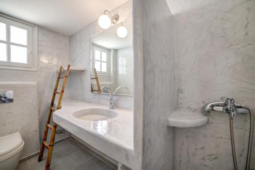 a white bathroom with a sink and a toilet at MONOLiTHIA in Kamari