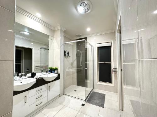 a white bathroom with two sinks and a shower at Luxury Holiday Home in Middle Ridge Toowoomba in Harristown