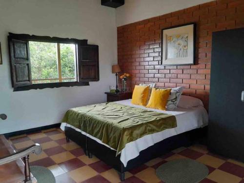 Un dormitorio con una cama y una pared de ladrillo. en Finca cafetera para tu descanso-Finlandia Quindio, en Filandia