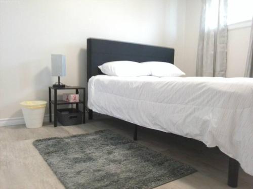 um quarto com uma cama grande com lençóis brancos e um tapete em Sweethome - 10 min to Rogers Place & so much more em Edmonton