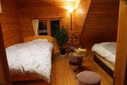 a bedroom with two beds and a teddy bear in a cabin at Log house Tomi-chan's house / Private building in Echizen