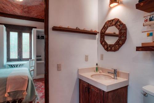 a bathroom with a sink and a bed and a mirror at Casa Hacienda in Sayulita