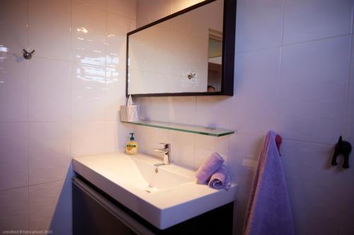 uma casa de banho com um lavatório branco e um espelho. em Tropical Villa Rainville em Paramaribo