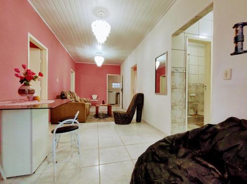 - un salon aux murs roses avec une table et des chaises dans l'établissement Apto 3 quartos 500m do mar, churrasqueira e varanda com vista para o pôr do sol, à São Francisco do Sul