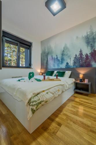 a bedroom with a large bed with a painting on the wall at Apartman Maska in Zlatibor