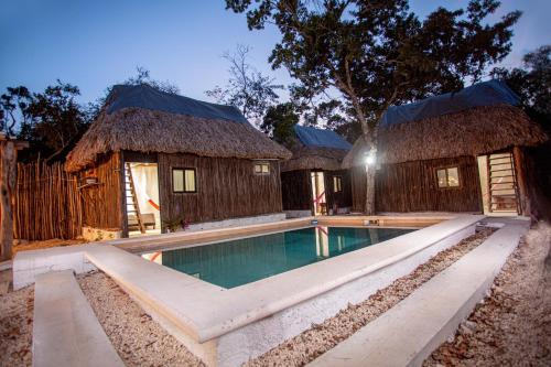 a resort with a swimming pool and two huts at Cabañas Casvar in Balcheil