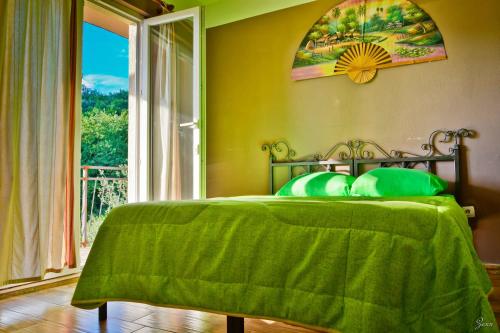 a bedroom with a bed with a green blanket and a window at Hostel Anton in Tivat