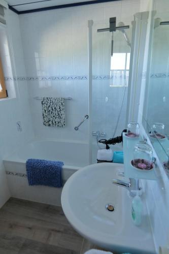 a white bathroom with a sink and a bath tub at Ferienhaus Haas inkl. Chiemgaukarte in Ruhpolding