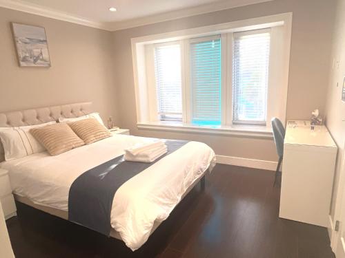 a bedroom with a bed and a desk and two windows at Near Skytrain Private Bedroom Ensuite BathRM, Free Wifi & Coffee, Cozy in Burnaby