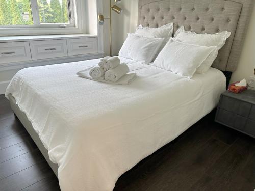 a white bed with two rolls of towels on it at Haven Tree Sweet Home in Richmond