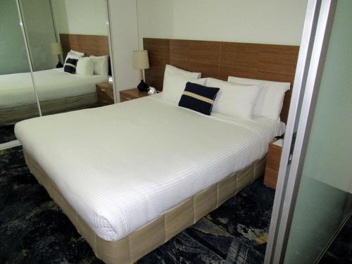 a bedroom with a large white bed with a mirror at Lovely One Bedroom Apartment "Cairns Harbour Lights" in Cairns