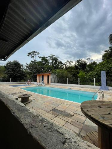 una piscina con una mesa delante en Chácara Recreio São Luiz do Paraitinga, en São Luís do Paraitinga