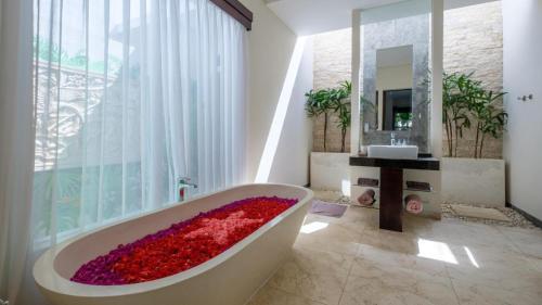 La salle de bains est pourvue d'une baignoire remplie de fleurs rouges. dans l'établissement Athena 2 Romantic 1br Pool Villa SANUR, à anur