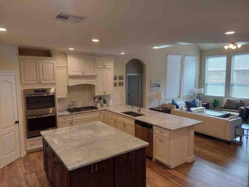 a large kitchen with white cabinets and a living room at 4 Bedroom - Luxury Home and Bedding -Sleeps 9 in Humble