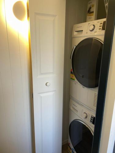 a kitchen with a microwave and a washer and dryer at The Cottage in Queenstown
