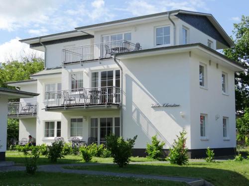 ein weißes Haus mit Balkon und Hof in der Unterkunft Strandhotel Villa Louisa & Appartementhäuser Villa Josephine und Villa Christine in Juliusruh