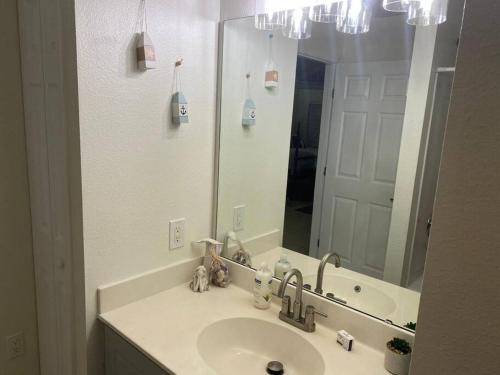 Un baño con lavabo y un espejo grande. en Disney Kissimmee Condo, en Kissimmee