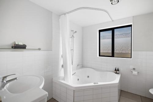 La salle de bains blanche est pourvue d'une baignoire et d'un lavabo. dans l'établissement Avenue Motel, à Alexandra